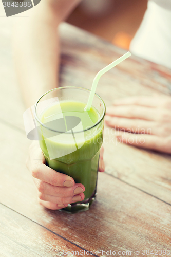 Image of close up of woman hands with green juice