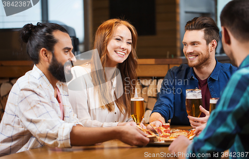 Image of friends eating pizza with beer at restaurant