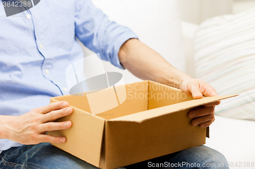 Image of close up of man with cardboard box parcel at home