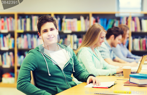 Image of happy student boy reading books in library