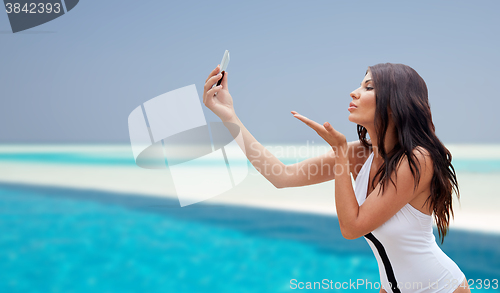 Image of young woman taking selfie with smartphone