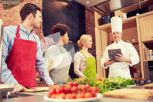 Image of happy friends with tablet pc in kitchen