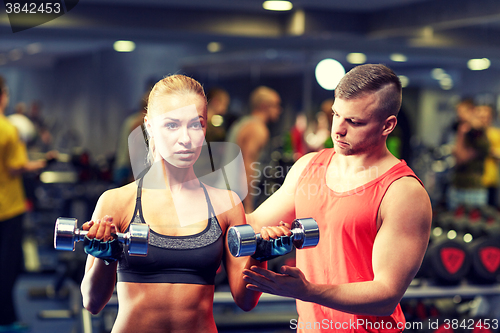 Image of young couple with dumbbells flexing muscles in gym