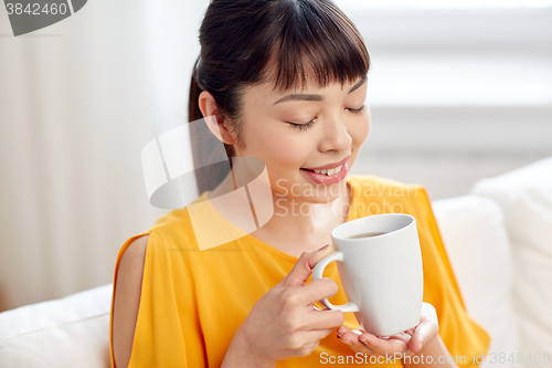 Image of happy asian woman drinking from tea cup