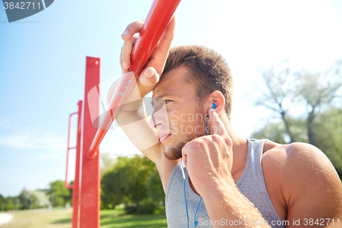 Image of young man with earphones and horizontal bar