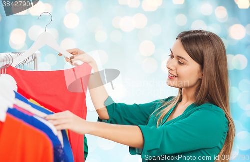 Image of happy woman choosing clothes at wardrobe