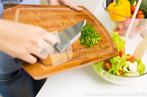 Image of close up of woman with chopped onion cooking salad