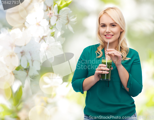 Image of smiling woman drinking vegetable juice or smoothie