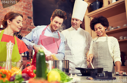 Image of happy friends and chef cook cooking in kitchen