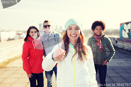 Image of happy friends pointing finger to you on street