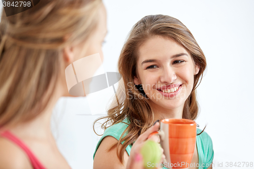 Image of happy young women drinking tea with sweets at home