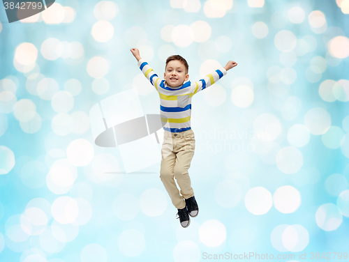 Image of happy little boy jumping in air over blue lights