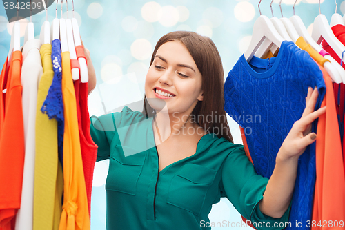 Image of happy woman choosing clothes at wardrobe