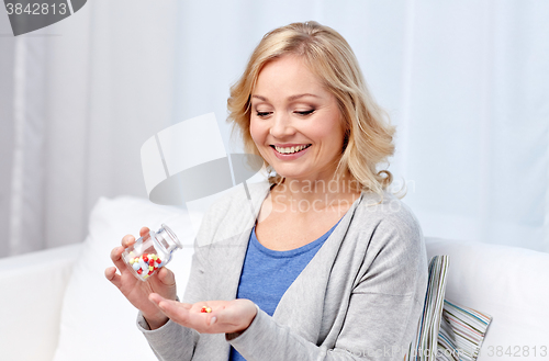 Image of happy middle aged woman with medicine at home