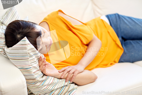 Image of happy asian teenage girl sleeping on sofa at home