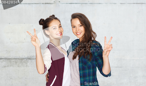 Image of happy teenage girls hugging and showing peace sign