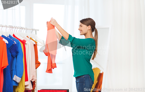 Image of happy woman with shopping bags and clothes at home