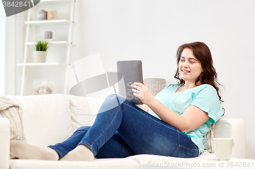 Image of happy young plus size woman with tablet pc at home