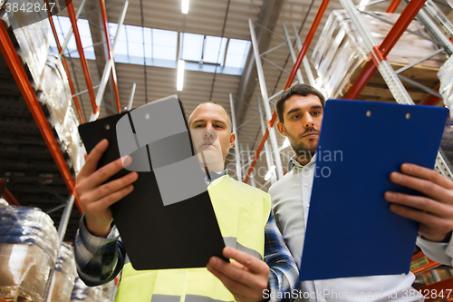 Image of worker and businessmen with clipboard at warehouse