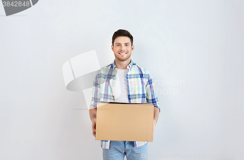 Image of smiling young man with cardboard box at home