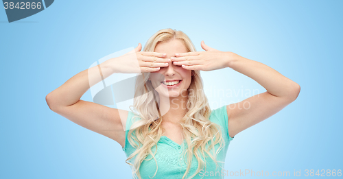 Image of smiling young woman or teen girl covering her eyes