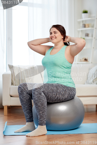 Image of plus size woman exercising with fitness ball