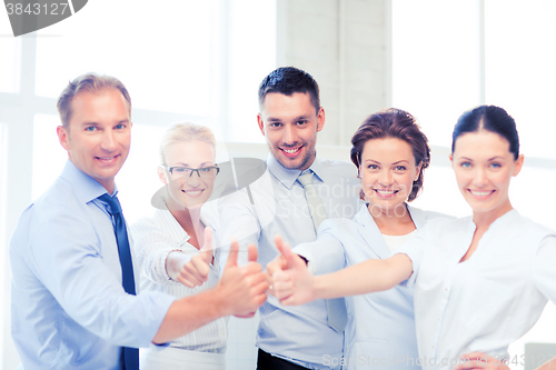 Image of business team showing thumbs up in office