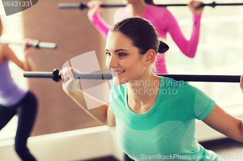 Image of group of people exercising with bars in gym