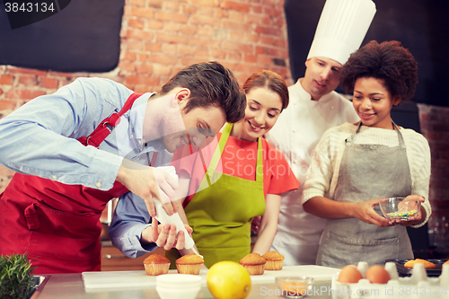 Image of happy friends and chef cook baking in kitchen