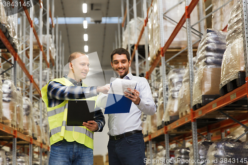 Image of worker and businessmen with clipboard at warehouse