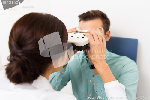 Image of optician with pupillometer and patient at clinic