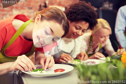 Image of happy women cooking and decorating dishes