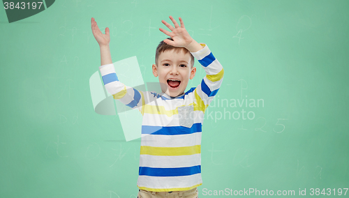 Image of happy boy waving hands over green school board