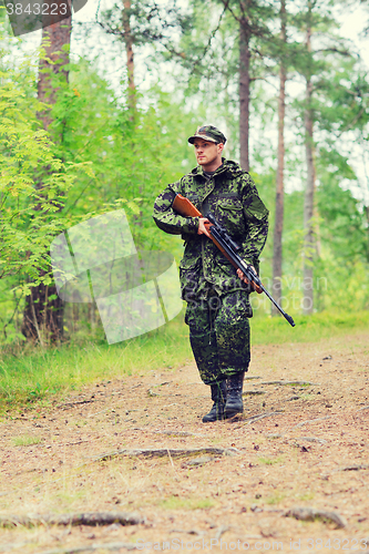 Image of young soldier or hunter with gun in forest