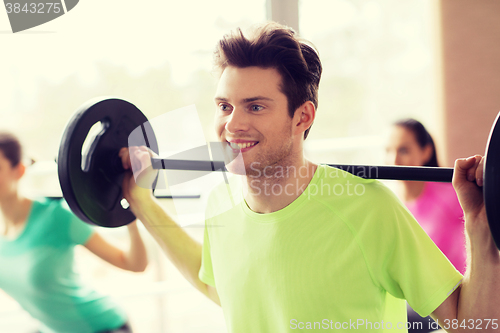 Image of group of people exercising with barbell in gym