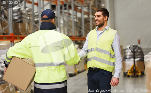 Image of men in safety vests shaking hands at warehouse