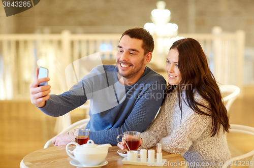 Image of couple taking smartphone selfie at cafe restaurant