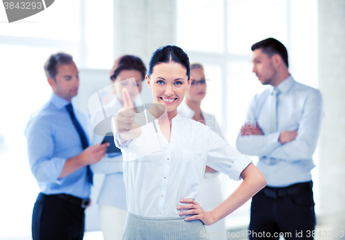 Image of businesswoman in office showing thumbs up