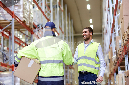 Image of men in safety vests shaking hands at warehouse