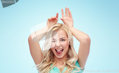 Image of happy smiling young woman making bunny ears