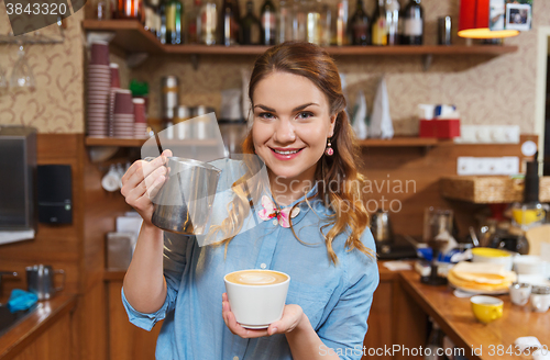 Image of barista woman pouring cream to cup at coffee shop