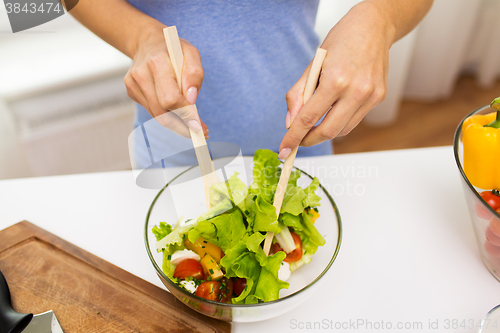 Image of close up of woman cooking vegetable salad at home