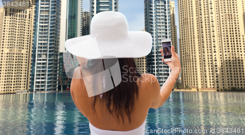 Image of woman taking selfie with smartphone over city pool