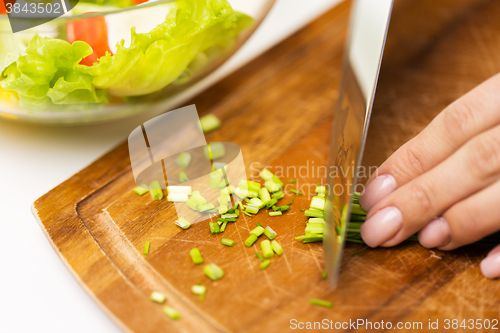 Image of close up of woman chopping green onion with knife