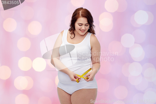 Image of happy young plus size woman with measuring tape