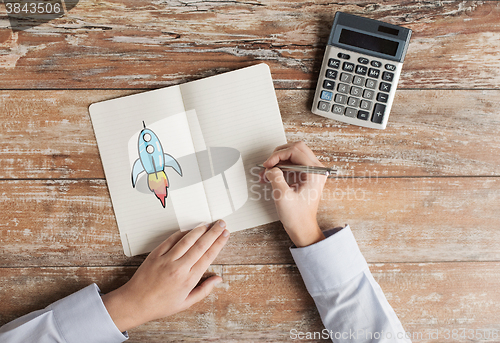 Image of close up of hands with calculator and notebook