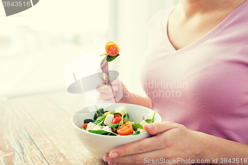 Image of close up of young woman eating salad at home