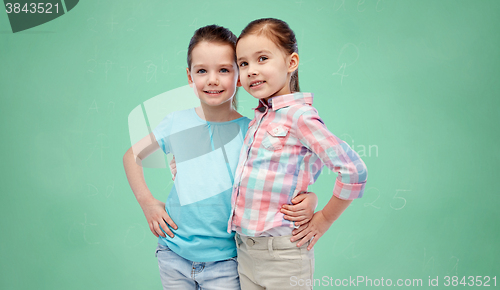 Image of smiling girls hugging over green school board