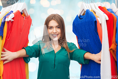 Image of happy woman choosing clothes at wardrobe