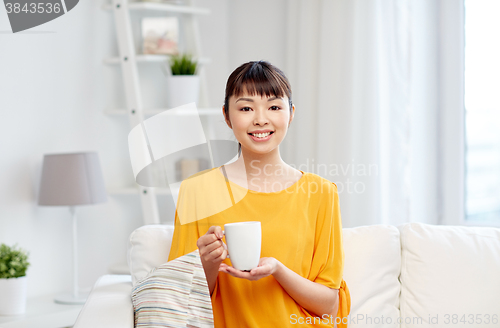 Image of happy asian woman drinking from tea cup